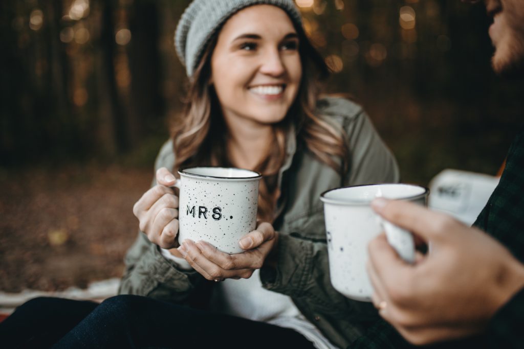 junge Frau Armyjacke grauer Mütze hält Kaffeetasse Hände von rechts andere Hand und Tasse