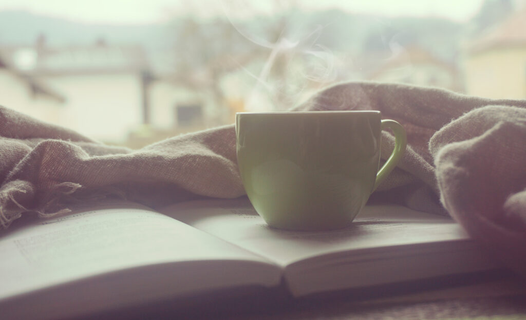 Aufgeklapptes Buch heisse Tasse Kaffee Blick aus Fenster